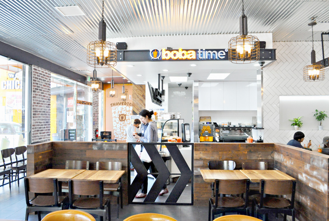 An interior perspective view of boba time store. exposed concrete floor. brick wall. people having boba
