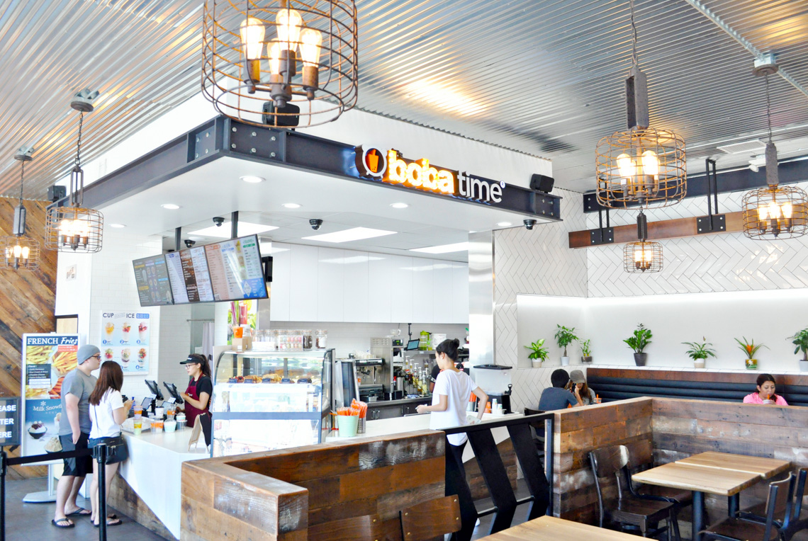 An interior perspective view of boba time store. exposed concrete floor. white tile wall. people having boba