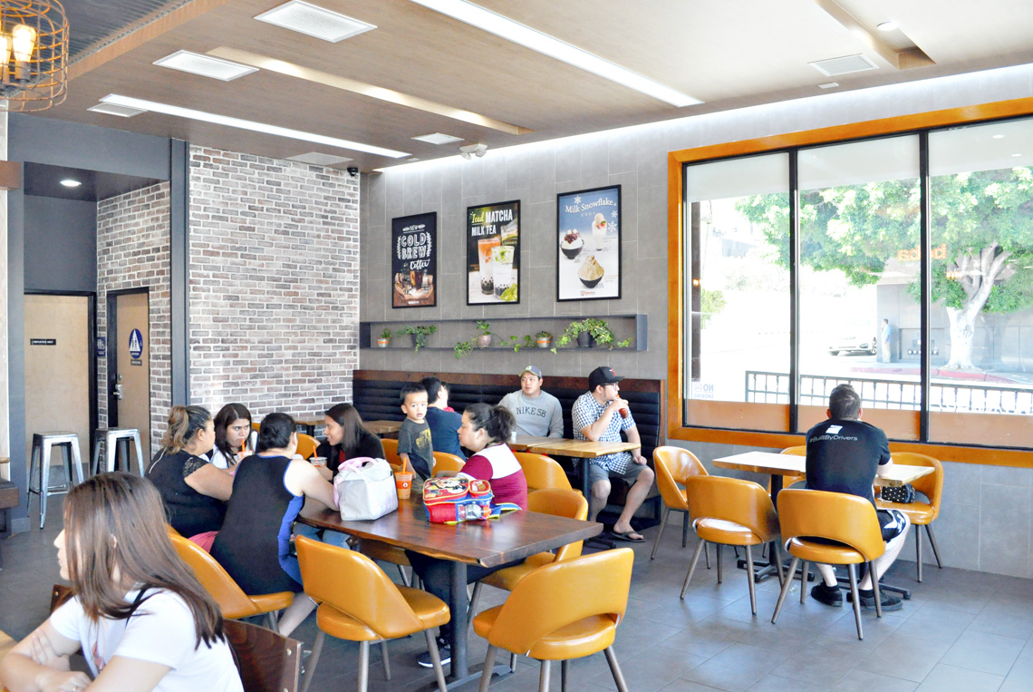 An interior perspective view of boba time store. exposed concrete floor. brick wall. people having boba