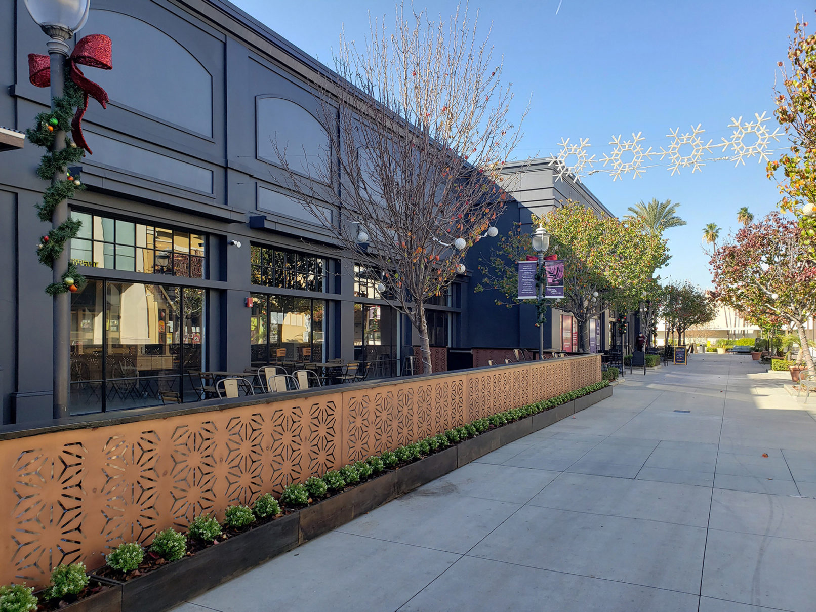 A building exterior picture. Storefront glazing and dark gray painted exterior wall. Exterior seating area in front of the building.