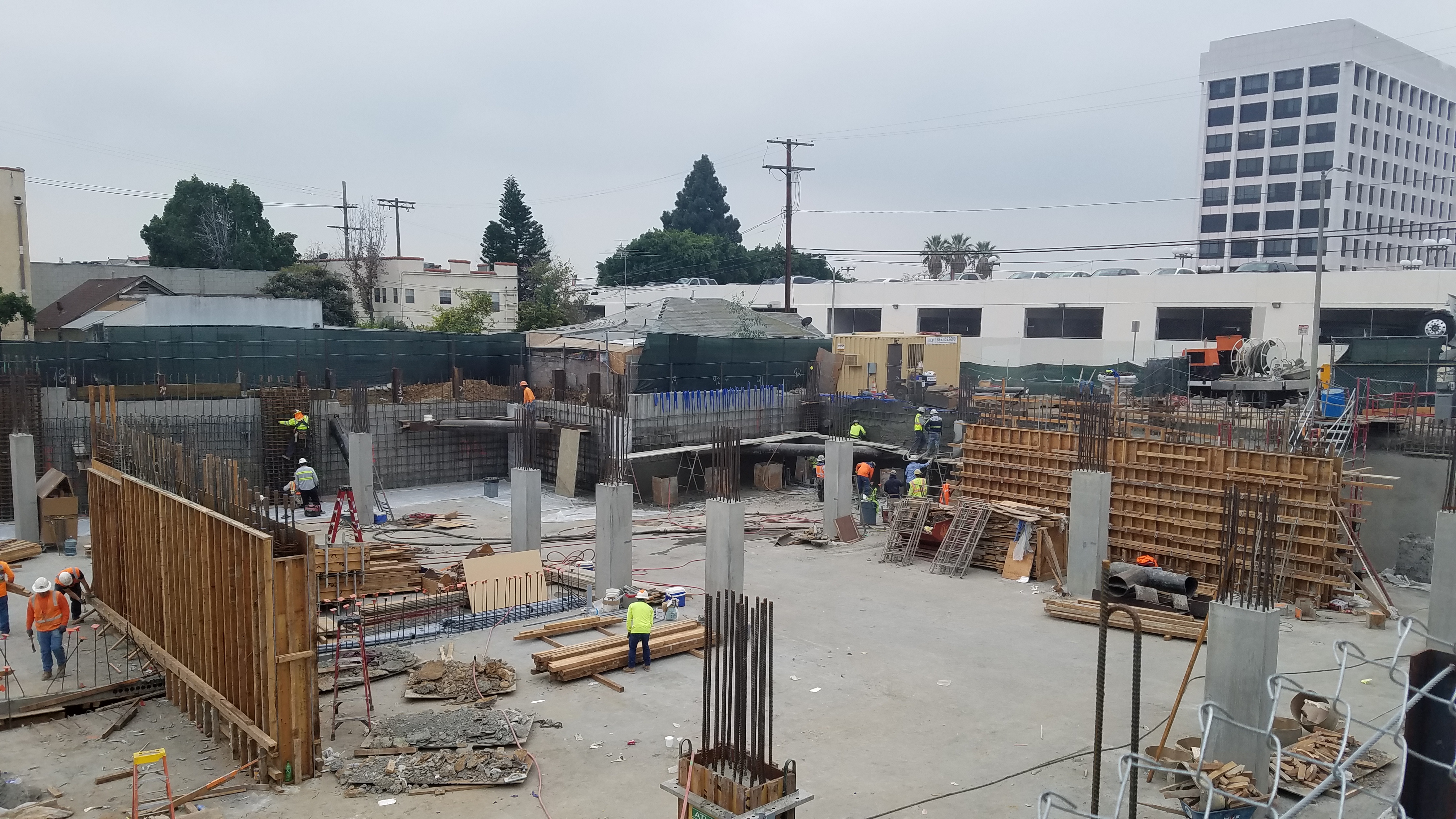 A construction photo of parking structure. An excavation and basement concrete wall. Concrete columns with rebars.