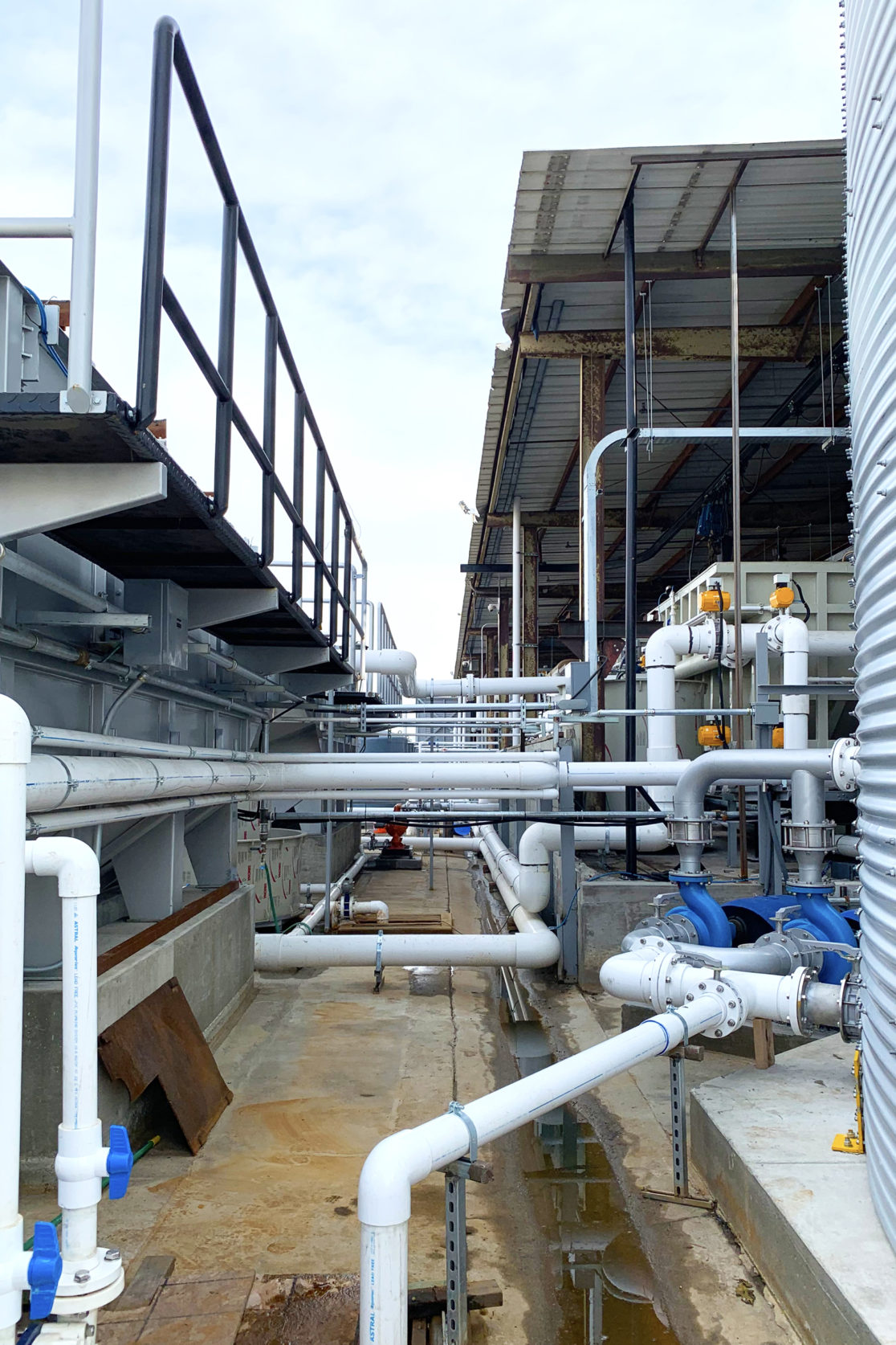 A building exterior picture of the water recycle facility. Pipes crossing the buildings.