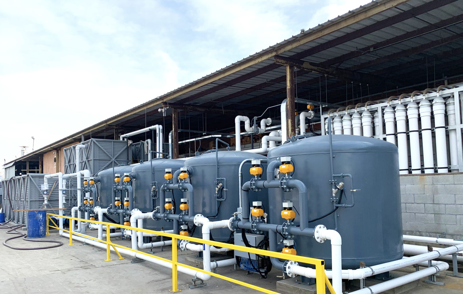 A building exterior picture of the water recycle facility. Pipes crossing the buildings.