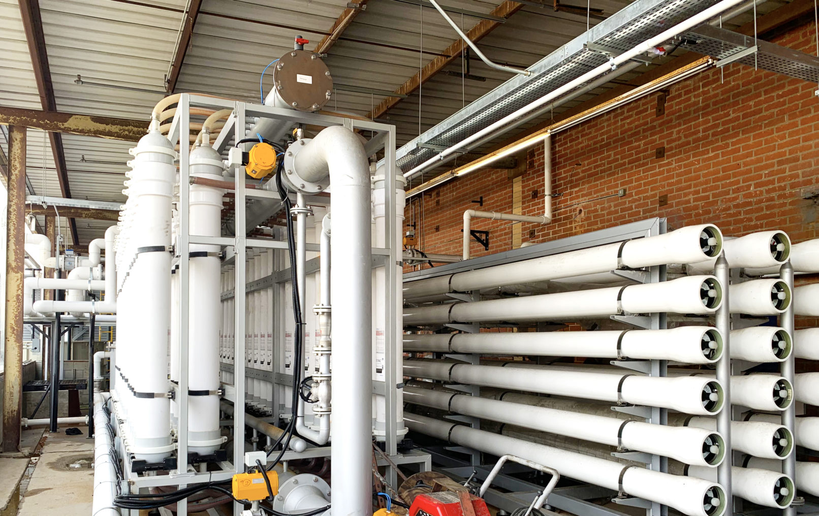 A building exterior picture of the water recycle facility. Pipes crossing the buildings.
