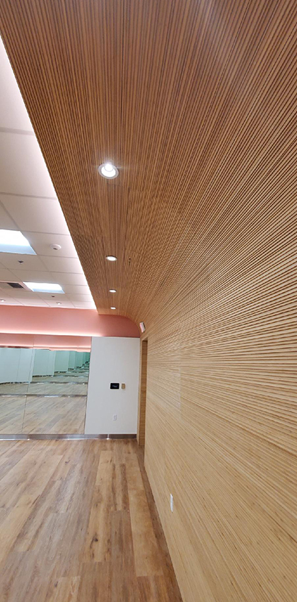 A construction photo of conference room. Wood floor finish and wooden slat wall.